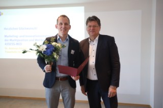 Neben Wissenschaftler Andreas Körtge mit Blumenstrauß und Urkunde steht der Wirtschaftsminister von Mecklenburg-Vorpommern Reinhard Meyer.